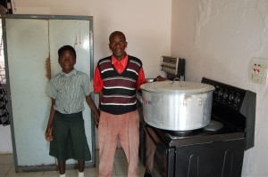 Thomas Silungwe stands with Christine Manda while preparing a meal on the newly installed electric stove. 